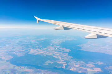 Obraz premium Aerial view from airplane window above green ground. View from the airplane window with beautiful clouds at sunrise