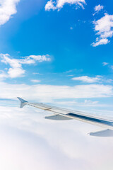 Fototapeta premium View from the airplane window at a beautiful cloudy sky and the airplane wing