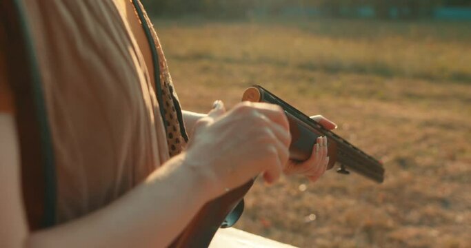 woman holding and reloading the rifle gun cropped video. girl loads rifle bullet for shooting target. Hunter loading bullet to carbine with optical-sight. Bullet shell. takes out cartridges from a gun