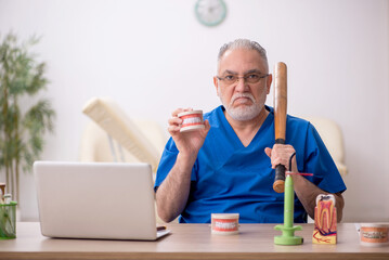 Old male dentist working in the clinic