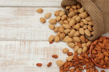 Bitter almond raw in shell, almond kernel, nuts in bag and clay bowl, on white table, background image, healthy food, background, photo, wallpaper, for presentations