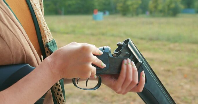 young woman putting cartridges into a gun before shooting. Skeet Shooting Sport.