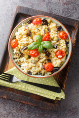 Millet porridge with eggplant, onions, tomatoes and basil close-up in a bowl on the table. Vertical top view from above