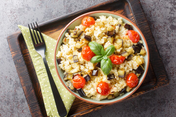 Tasty millet with tomato, eggplant, onions close-up in a bowl on the table. Horizontal top view from above