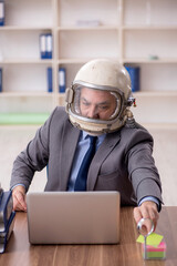 Old male employee wearing spacesuit in the office