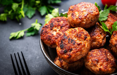 Homemade fried pork and beef meatballs in ceramic bowl, dark table background, top view, close-up