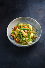 Green and white asparagus glazed with papaya in sweet vinaigrette served as close-up in a design plate with text space