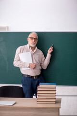 Old male teacher sitting in the classroom