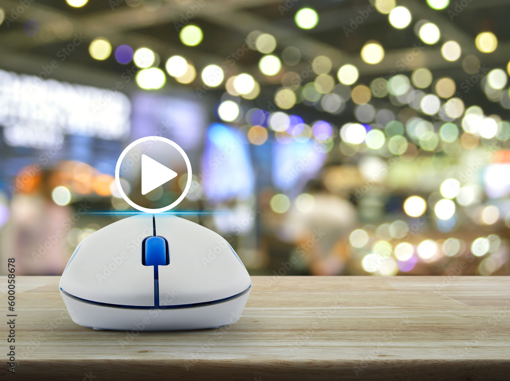 Poster play button with wireless computer mouse on wooden table over blur light and shadow of shopping mall