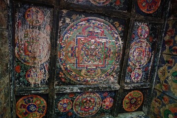 Capture the fading beauty of a Tibetan mandala Buddhist painting within a Manaslu Circuit stupa in the Nepalese Himalayas, radiating serenity and cultural richness.