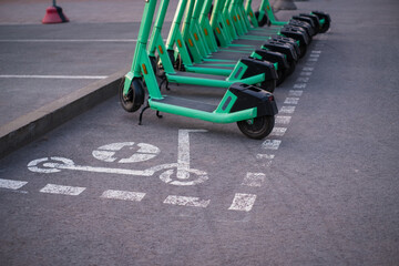 Green electric rent bikes parked in electric scooters parking area, marked with spray paint....