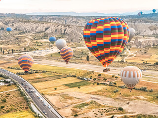 Flying in sky many bright colored beautiful balloons into air in Cappadocia in mountains early at...