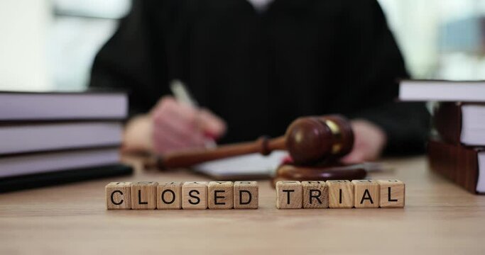 Word closed trial on wooden cubes next to judge with gavel in courtroom. Principle of public hearing