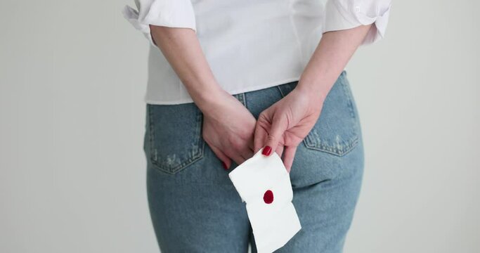 Woman holding toilet paper with blood stain closeup. Concept of hemorrhoids and menstruation