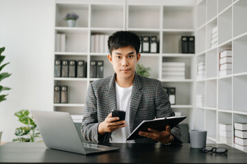Asian business man executive manager looking at laptop watching online webinar training or having virtual meeting video conference doing market research working in modern office.
