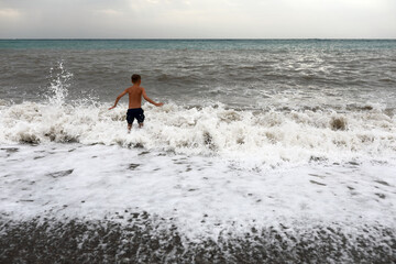 Child playing on shore of stormy Black Sea