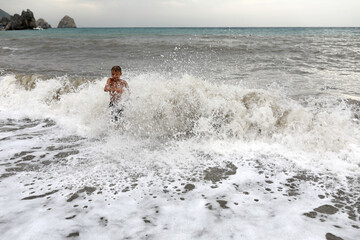 Child playing on shore of stormy Sea