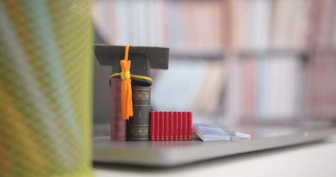 Graduate study abroad program to broaden learner's world view, e-learning concept : Graduation cap, foreign books on a laptop, depicts student attempting to study from a distance or learning from home