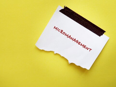 Torn note stick on yellow copy space background with text written MICROMANAGEMENT refer to management style which boss manager gives excessive supervision to employees, control every part of project