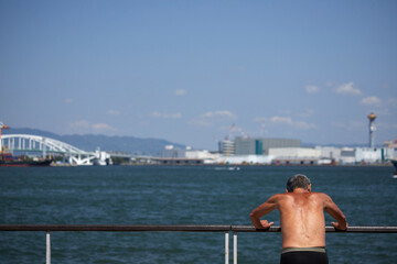 大阪湾の沿岸公園で運動しているシニア男性の背中