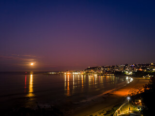 Fototapeta na wymiar Full moon Sunset, Mosselbay Harbour Wall, City Lights reflection, Santos Holliday Beach 