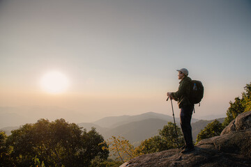 Young Man standing alone in forest outdoor with sunset nature on background Travel Lifestyle and survival concept.