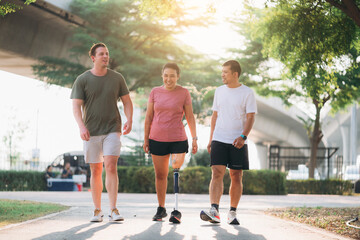 Woman exercising in a park with a friend providing support while using a prosthetic leg. People jogging side by side outside in a park. Female walking and exercise works out outside.
