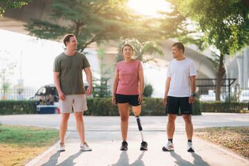 Woman exercising in a park with a friend providing support while using a prosthetic leg. People...