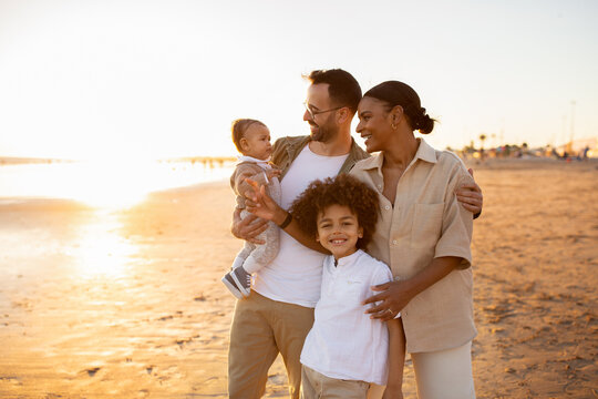 Beachside bonding. Happy multiracial family walking and enjoying time together on beach during holidays