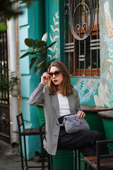 A beautiful girl works in a street cafe against a blue wall.