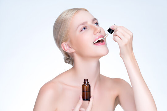 Closeup personable portrait of beautiful woman applying essential oil bottle for skincare product. Cannabis extracted CBD oil dropper for treatment and cannabinoids concept in isolated background.