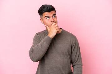 Young caucasian handsome man isolated on pink background having doubts and with confuse face expression