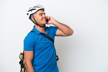 Young caucasian man with thermal backpack isolated on white background keeping a conversation with the mobile phone