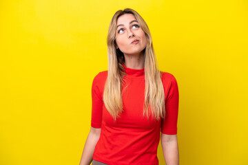 Young Uruguayan woman isolated on yellow background and looking up