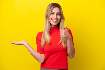 Young Uruguayan woman isolated on yellow background holding copyspace imaginary on the palm to...