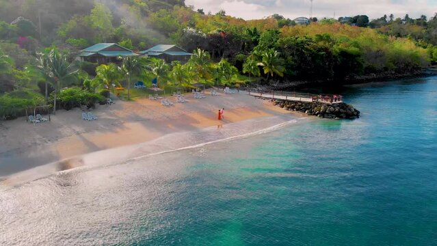 A couple of men and women walking on the beach at sunset at the beach of Saint Lucia Castries, St Lucia Tropical Island in the Caribbean at susnet