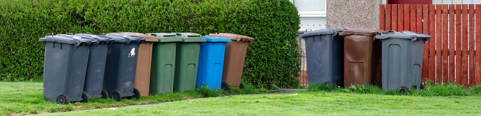 Wheelie bins in row for refuge collection outside council residential building