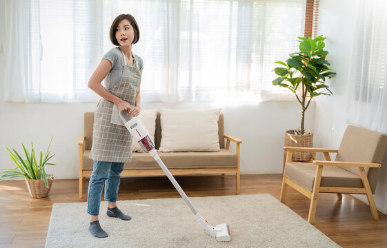 Portrait of young woman housewife hands holding mop cleaning floor with smart object technology in modern living room. Daily routine cleaning. Domestic housework service concept