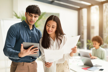 Two diverse business people using tablet interacting working in office