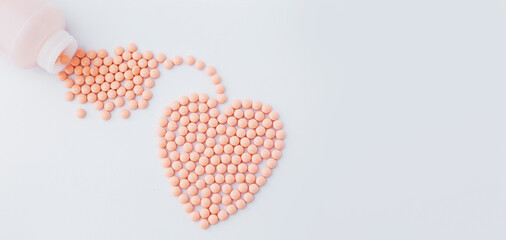 Pink pills, vitamins in the shape of heart on white background. Vitamin supplements for the heart. 