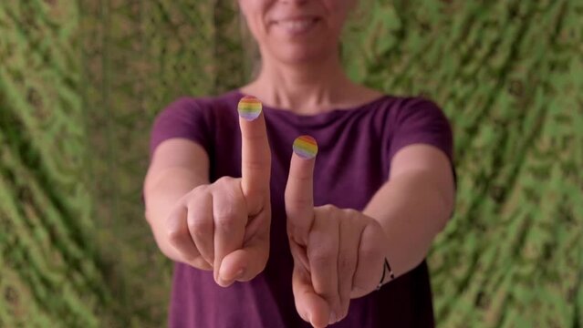 happy beautiful woman, dancing, moves her fingers to the music with lgtbi pride flag symbols
