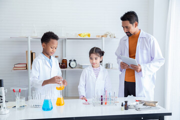 Elementary education lifestyle for students concept, Multi-ethnicity kids happy in science class in laboratory lab with microscope and tube experiments, kids in white coat enjoy with Hispanic teacher