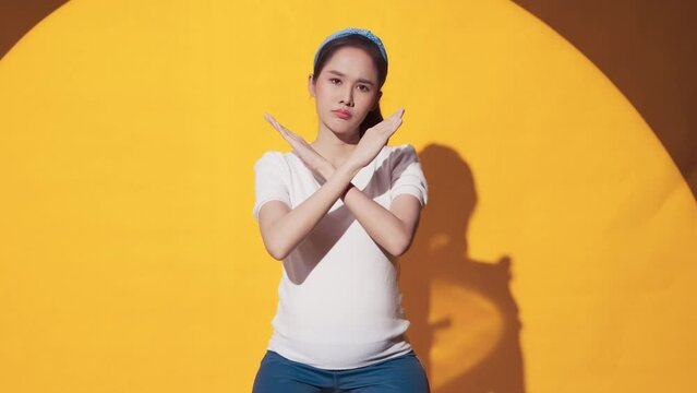 confused and say no hand gesture sign asian female pregnant woman listen look at camera while hand rising up make x cross symbol for refuse or say no to camera studio shot,pregnant woman hand defense