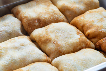 Pancake envelopes filled with chicken, mushrooms, and paprika ready to be baked in the oven