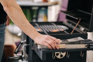 Close-up of man's hand put metal grill tongs to the side stand