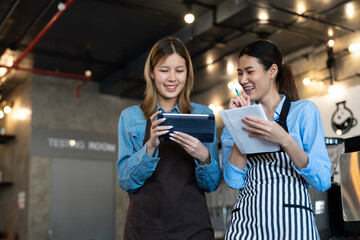 Happy two young female baristas in aprons learning to make coffee and business coffee shop