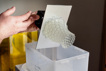 Man using a wash machine to clean a transparent 3d resin object