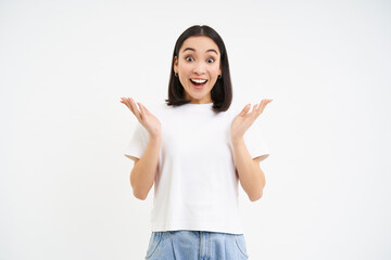 Enthusiastic asian woma, clap hands and smiles with surprised, happy face, congratulating, praising, standing over white background - obrazy, fototapety, plakaty