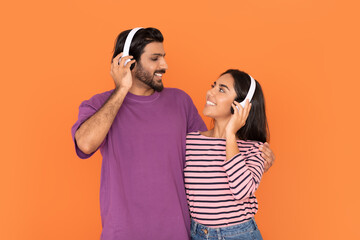 Happy young indian couple in wireless headphones listening music