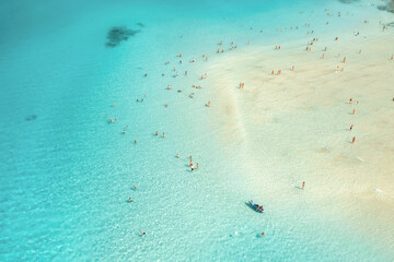 Aerial view of blue sea and sandy beach with crowd of people in the morning at dawn in summer. Beautiful seascape, vacation background. Landscape top view